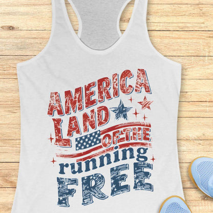 White tank top with 'America Land of the running Free' text and American flag design on a wooden surface.