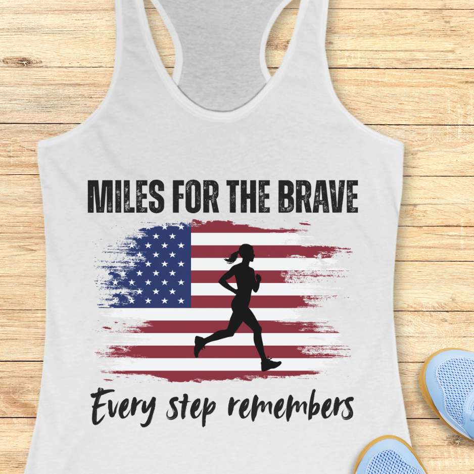 Gray tank top with 'Miles for the Brave' design featuring an American flag and running silhouette on a wooden surface.