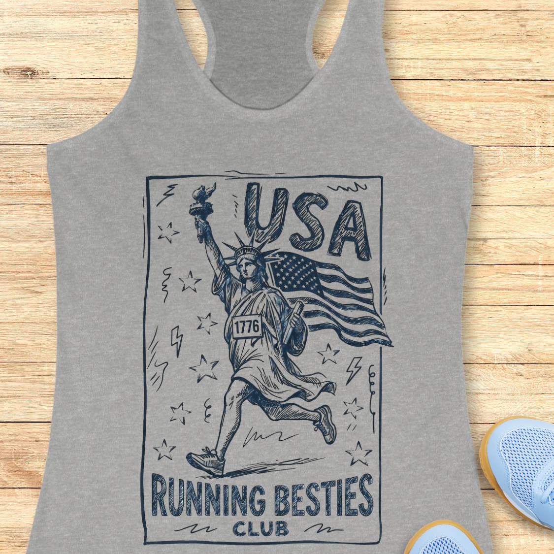 Gray tank top with 'USA Running Besties Club' graphic on a wooden surface