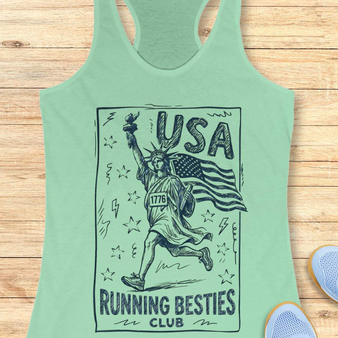 Mint green tank top with 'USA Running Besties Club' design on a wooden surface