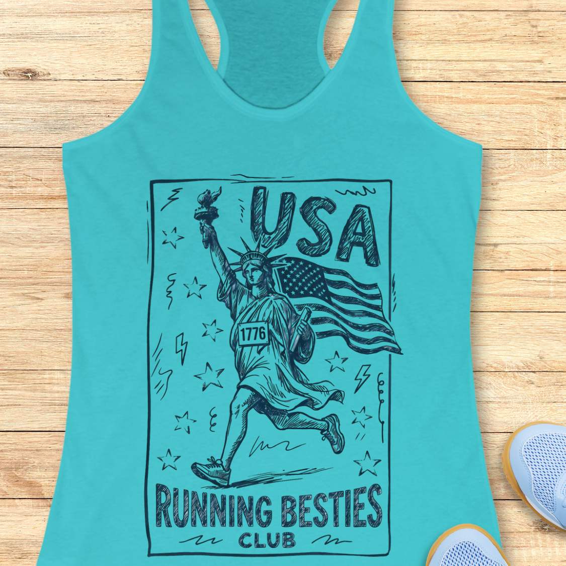 Turquoise tank top with 'USA Running Besties Club' design on a wooden surface