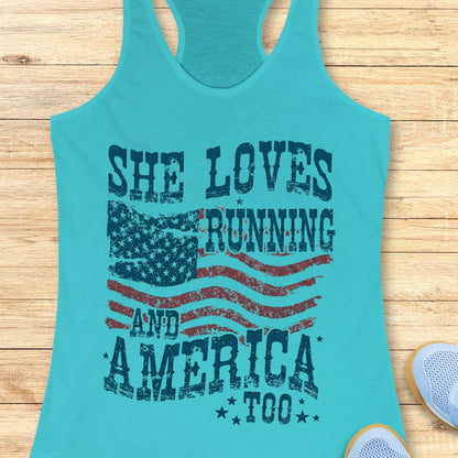 Turquoise tank top with 'She Loves Running and America Too' text and American flag design on a wooden surface.