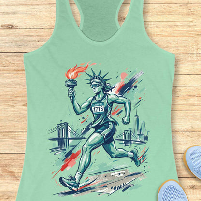 Mint green tank top with a graphic design of a running Lady Liberty holding a torch on a wooden surface.
