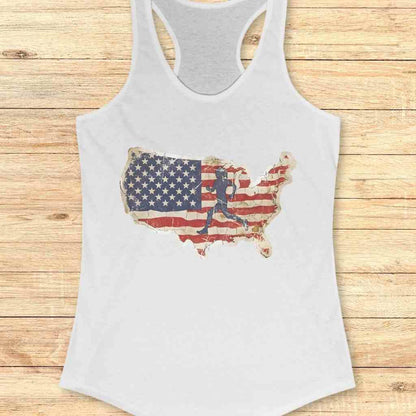 White racerback tank top with a distressed United States map graphic filled with a weathered American flag pattern and a dark silhouette of a runner, presented on a rustic wooden plank surface