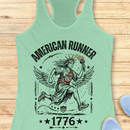 mint tank top with a design of lady liberty running and text - 'American runner 1776', on a wooden surface.