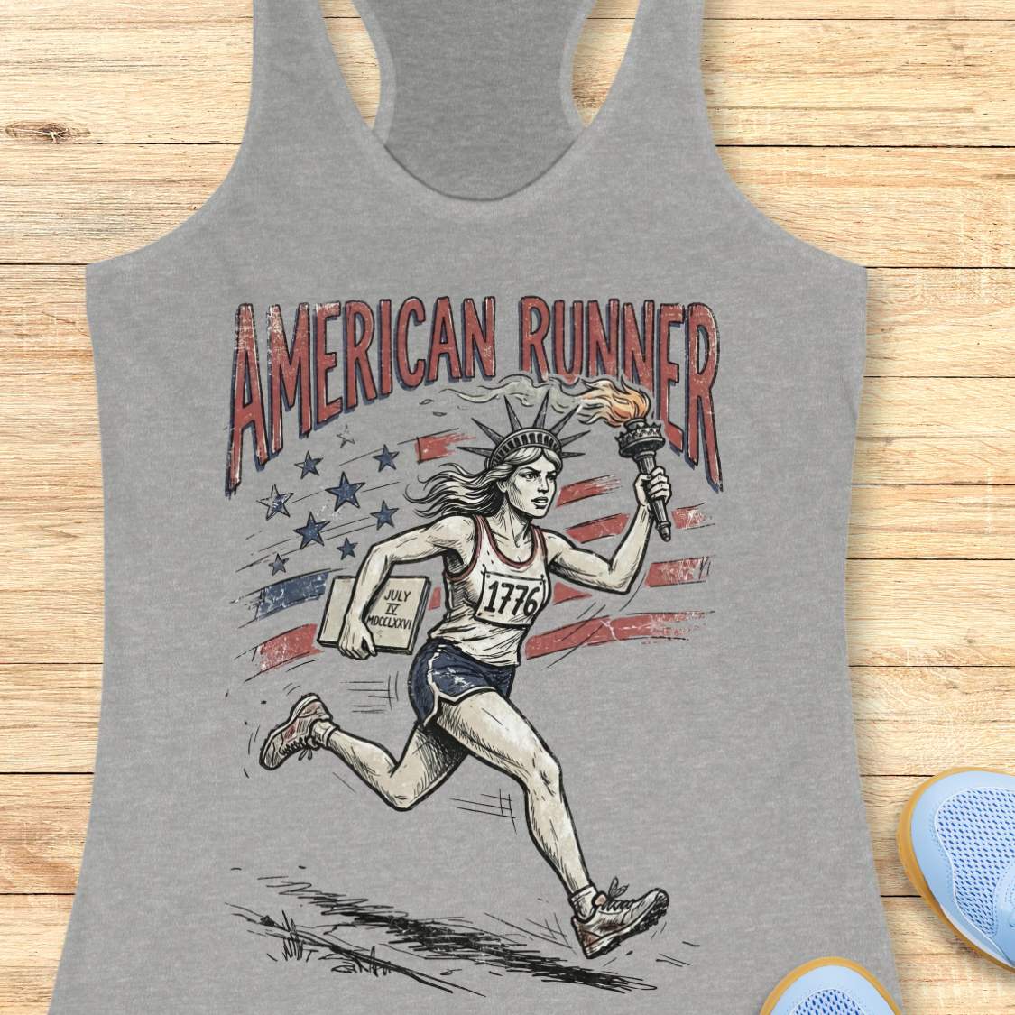 grey tank top with a design of lady liberty running and text - 'American runner', on a wooden surface.