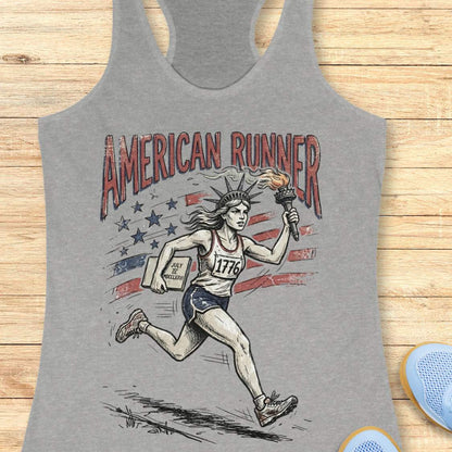 grey tank top with a design of lady liberty running and text - 'American runner', on a wooden surface.