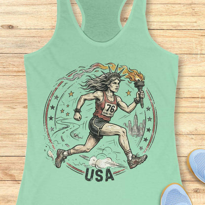 Mint green tank top with a graphic design of a lady liberty as a runner and 'USA' text on a wooden surface.