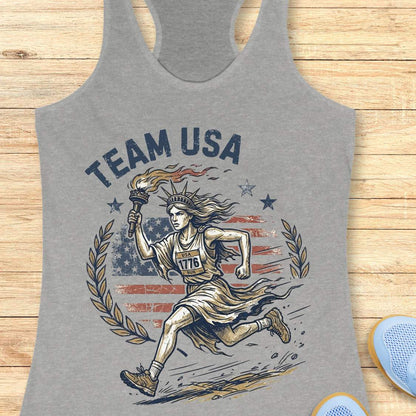 Gray tank top with 'Team USA' design featuring lady liberty running and American flag on a wooden surface.