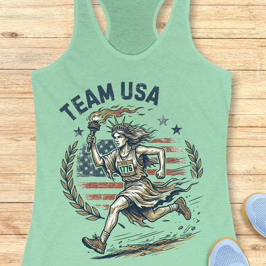 Green tank top with 'Team USA' design featuring lady liberty running and American flag on a wooden surface.