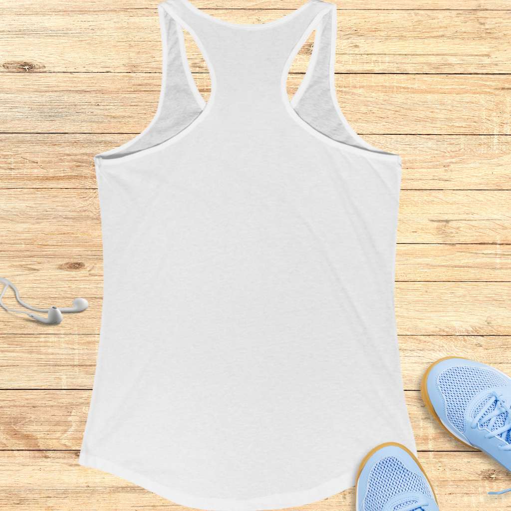 White tank top on a wooden surface with blue sneakers and earphones.