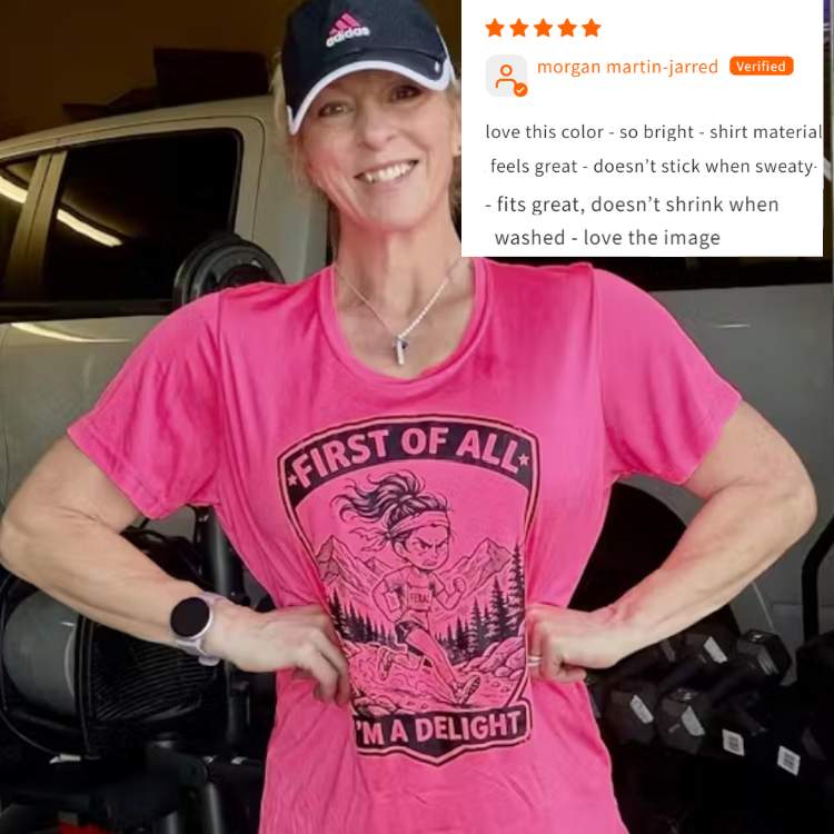 Woman wearing a pink t-shirt with a graphic design and text, standing in a garage.
