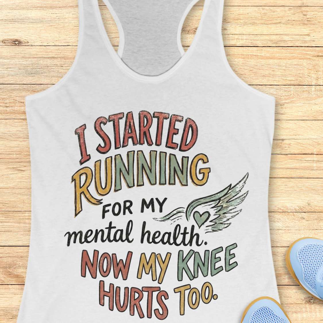 White tank top with motivational quote on a wooden surface