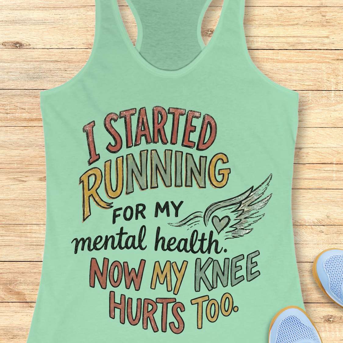 Mint green tank top with motivational quote on a wooden surface