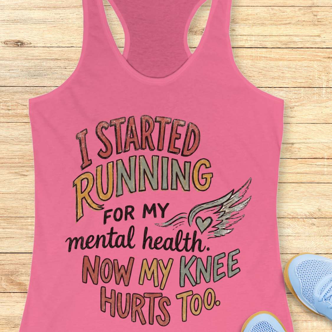 Pink tank top with humorous text on a wooden surface