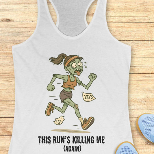 White racerback tank top displaying a humorous cartoon zombie runner with green skin, tattered brown clothes, race bibs 131 and 1313, and the slogan 'THIS RUN'S KILLING ME (AGAIN)' set against a light wooden background with partial blue running shoes and white earbuds visible