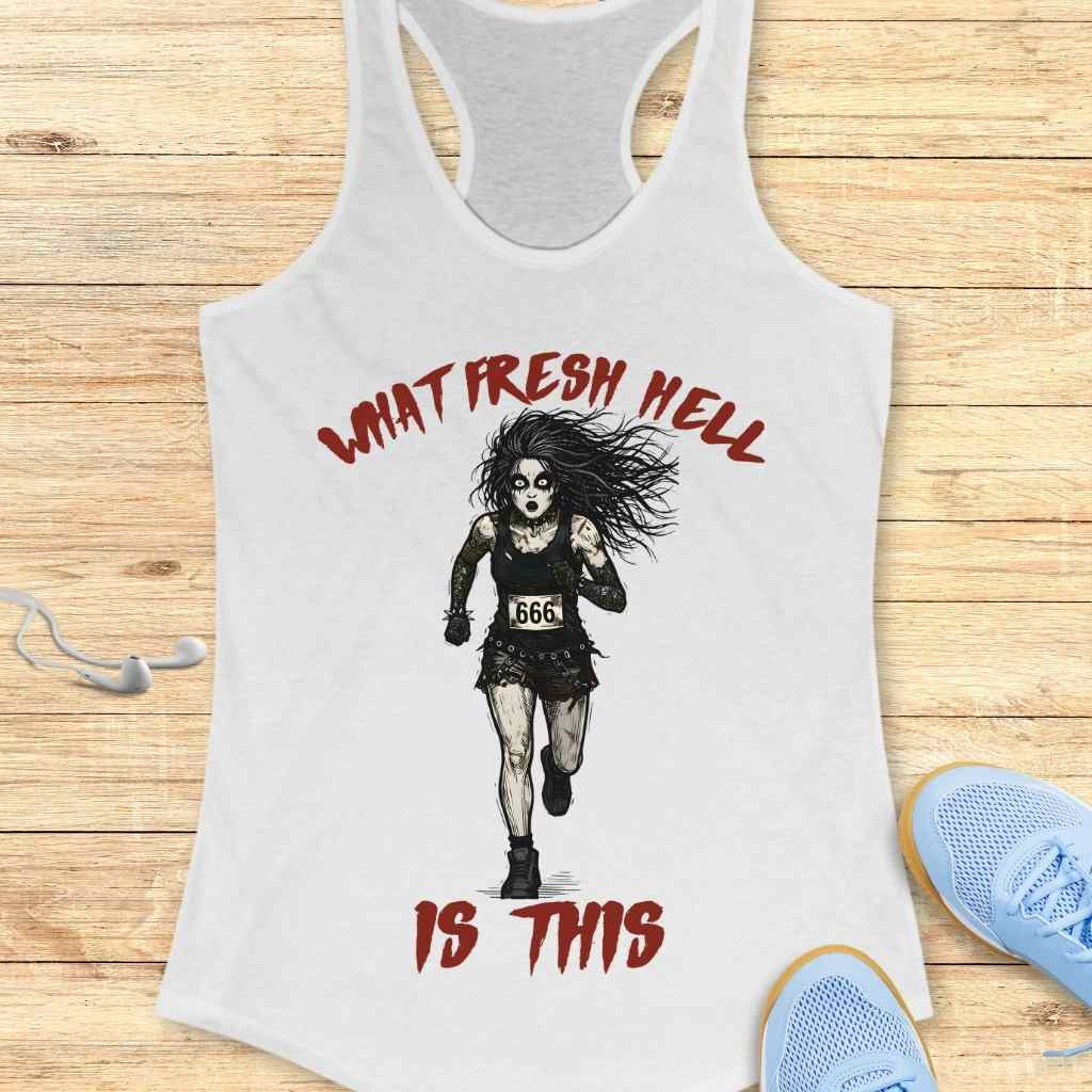White racerback tank top depicting a distressed zombie-like woman running with a 666 bib and wild hair, surrounded by red 'What Fresh Hell Is This' text, displayed on a wood floor next to white earbuds and blue sneakers