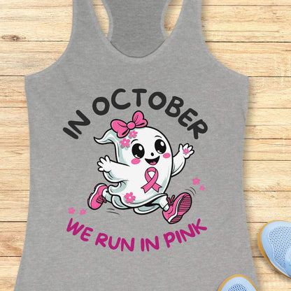 grey tank top with a cartoon ghost and pink ribbon design with the text - 'in October we run in pink', on a wooden surface.