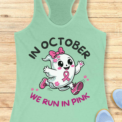 mint tank top with a cartoon ghost and pink ribbon design with the text - 'in October we run in pink', on a wooden surface.