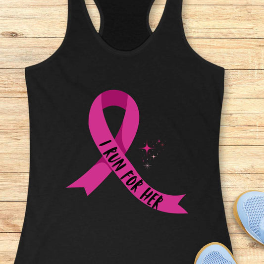 Black tank top with pink ribbon and 'I Run for Her' text on a wooden surface with sneakers and earphones.