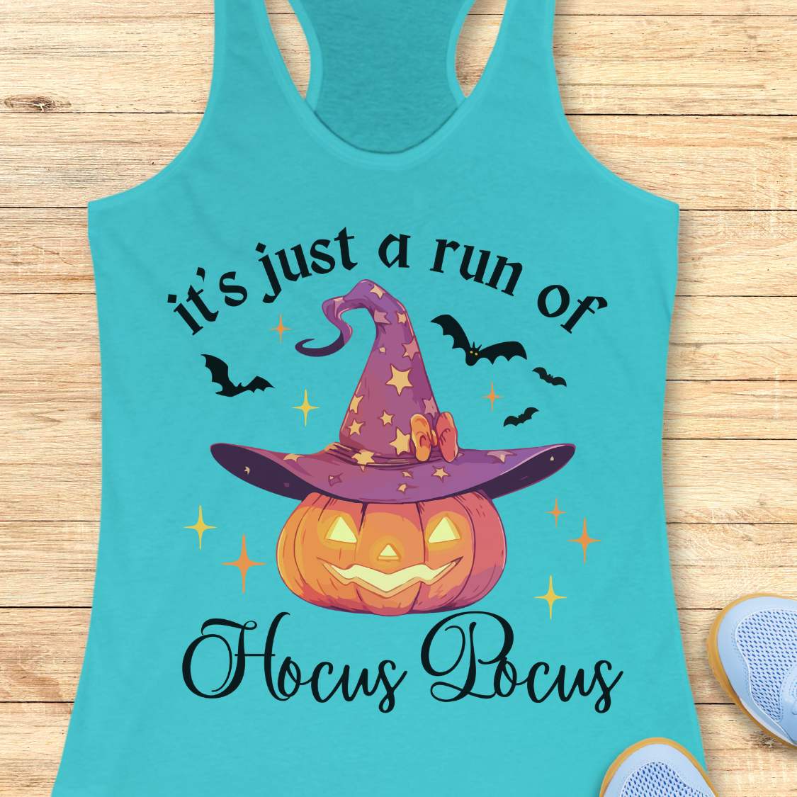 blue tank top with Halloween design featuring a pumpkin and witch hat on a wooden surface.
