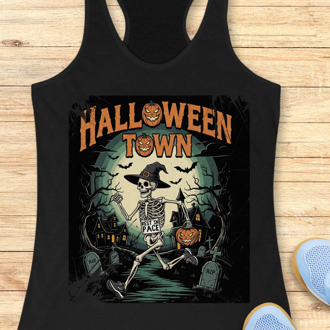 Black tank top with Halloween-themed design and a text ' Halloween town', on a wooden surface
