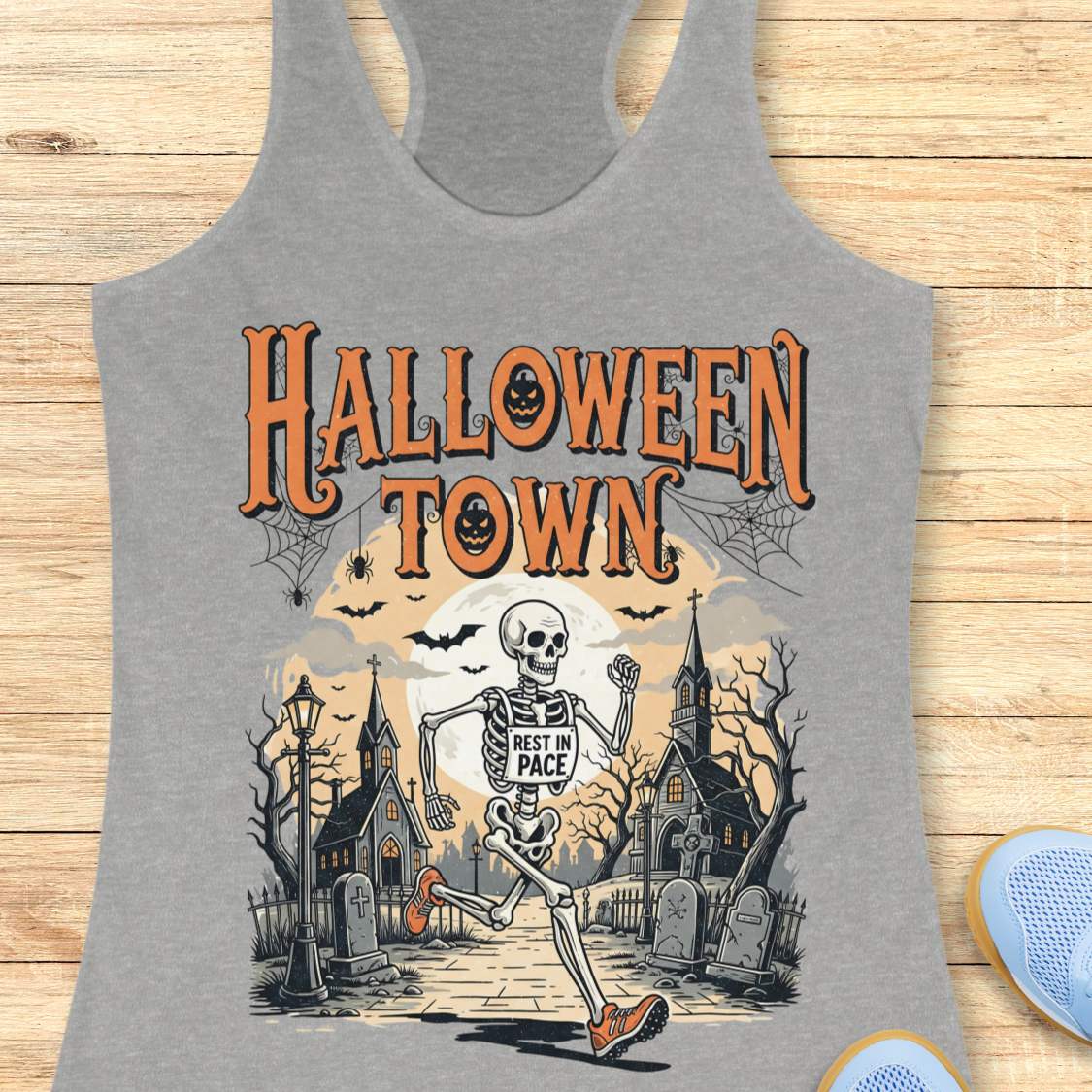 grey tank top with Halloween-themed design and a text ' Halloween town', on a wooden surface