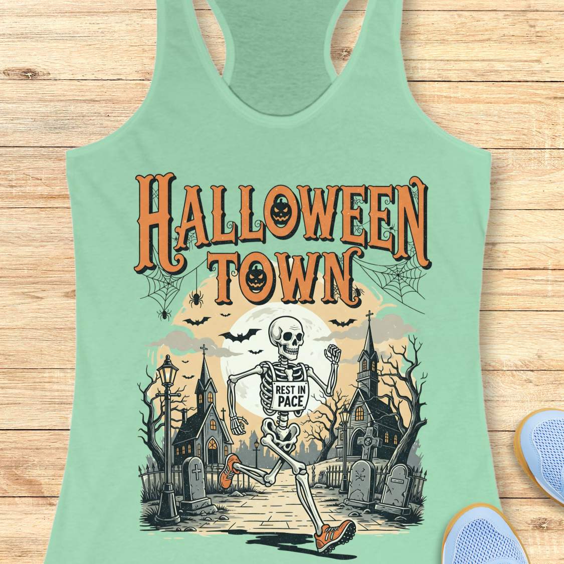 mint tank top with Halloween-themed design and a text ' Halloween town', on a wooden surface