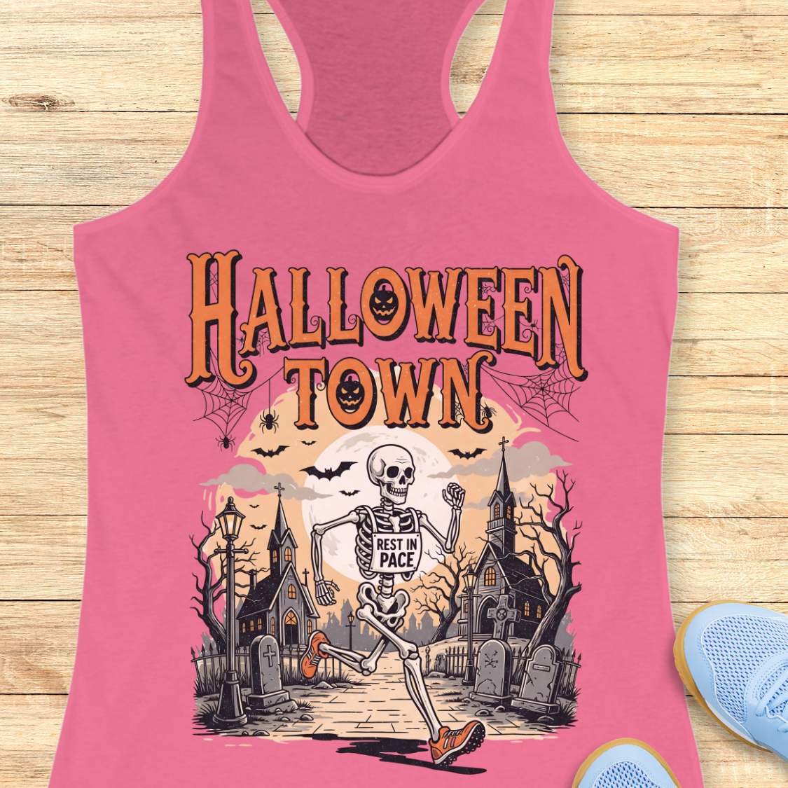 pink tank top with Halloween-themed design and a text ' Halloween town', on a wooden surface