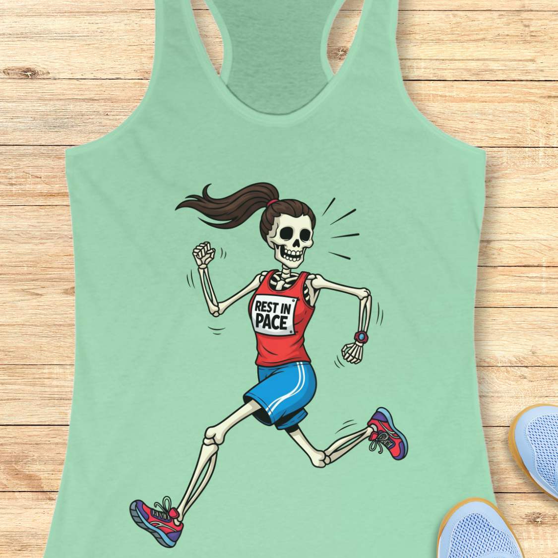 Graphic design on a mint tank top featuring a female skeleton with a ponytail running in a red 'REST IN PACE' top, blue shorts, colorful athletic shoes, and a fitness watch, laid flat on a light wood surface with white earbuds and light blue sneakers