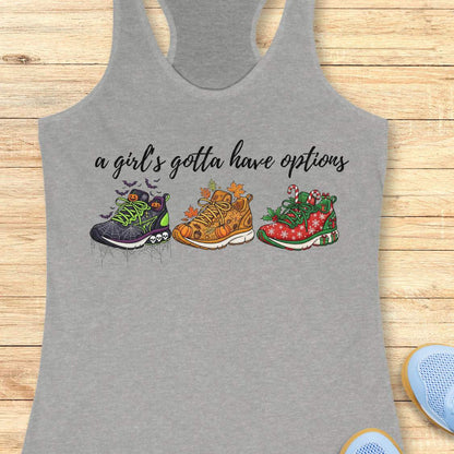 grey tank top with running shoes designs and text 'a girl's gotta have options',  on a wooden surface
