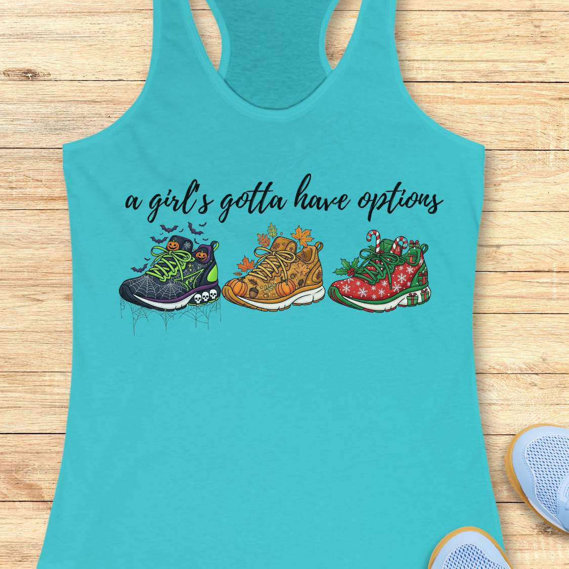 blue tank top with running shoes designs and text 'a girl's gotta have options',  on a wooden surface