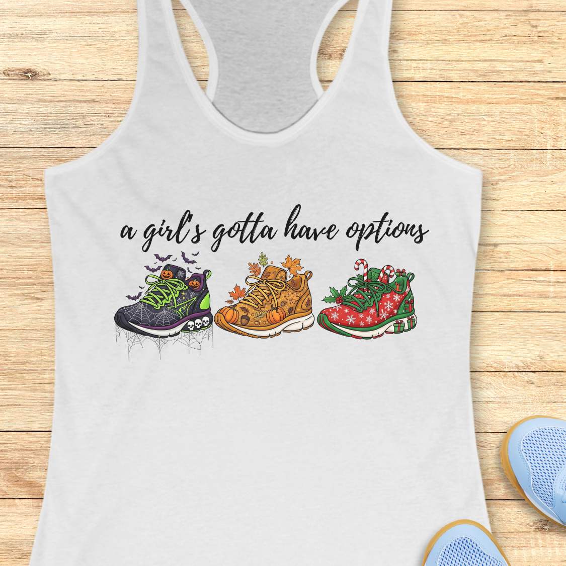 white tank top with running shoes designs and text 'a girl's gotta have options',  on a wooden surface