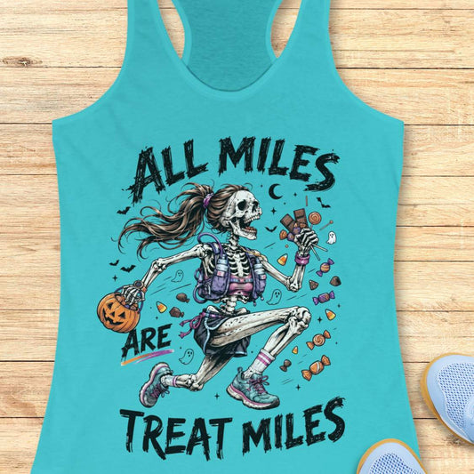 A turquoise racerback tank top laid flat on a light wood surface, featuring a colorful Halloween graphic of a skeleton girl holding a pumpkin and candy, with the text 'ALL MILES ARE TREAT MILES'. A partial blue shoe is visible at the bottom right.