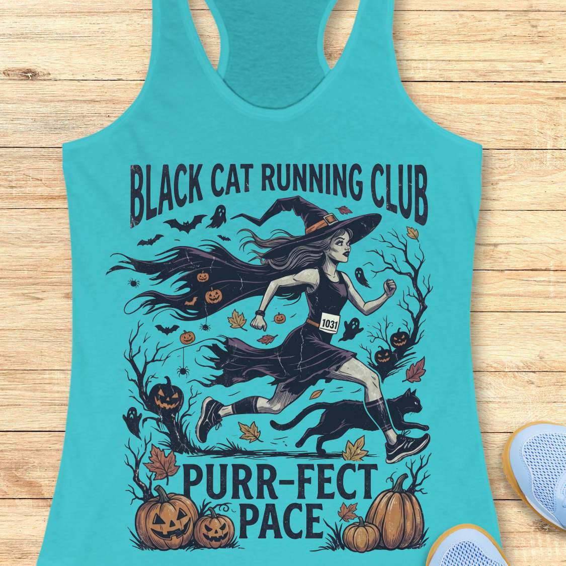A turquoise racerback tank top laid flat on a light wood surface, featuring a Halloween graphic of a witch running with a black cat and pumpkins, with the text 'BLACK CAT RUNNING CLUB' and 'PURR-FECT PACE'.