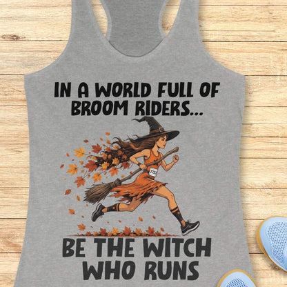 A heather gray racerback tank top featuring a graphic of a woman running on a broomstick with autumn leaves, with the text 'IN A WORLD FULL OF BROOM RIDERS.