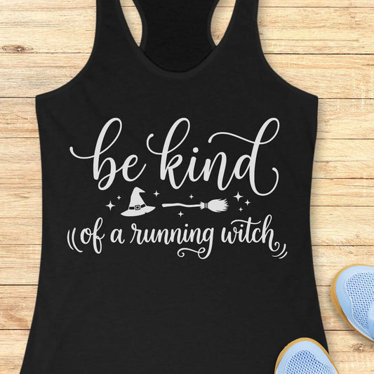 A black racerback tank top with a black graphic print reading 'be kind of a running witch' with a witch hat, broom, and stars, displayed flat on a light wood background with partial sneakers visible at the edges.