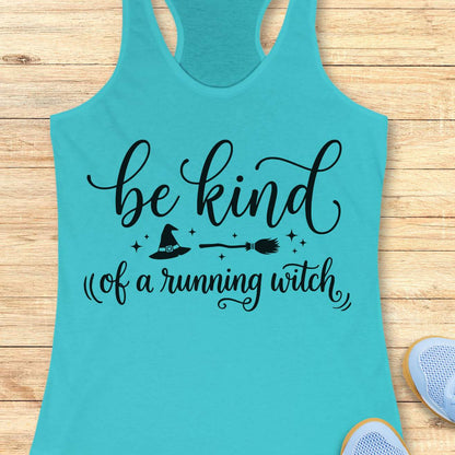 A turquoise racerback tank top laid flat on a light wood surface, printed with the phrase "be kind of a running witch" in black script and small witch-themed graphics including a hat, broom, and stars. Partial sneakers are visible at the bottom right as styling props.