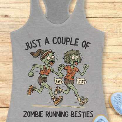 grey racerback tank top featuring the phrase “JUST A COUPLE OF” above two cartoon zombie runners and “ZOMBIE RUNNING BESTIES” below. The two zombie friends are running side by side wearing race bibs numbered 1313 and 1313B, with tattered running clothes, messy hair, and humorous zombie details. The playful Halloween-themed design combines friendship and running with a spooky, fun aesthetic perfect for runners who love Halloween.