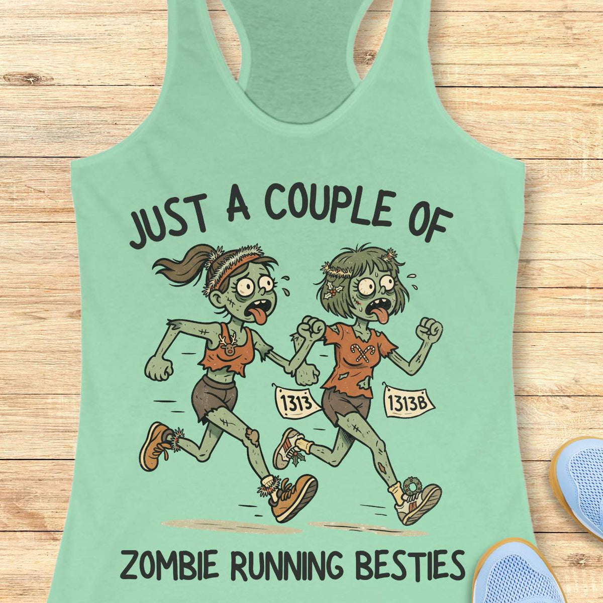 Mint green racerback tank top featuring the phrase “JUST A COUPLE OF” above two cartoon zombie runners and “ZOMBIE RUNNING BESTIES” below. The two zombie friends are running side by side wearing race bibs numbered 1313 and 1313B, with tattered running clothes, messy hair, and humorous zombie details. The playful Halloween-themed design combines friendship and running with a spooky, fun aesthetic perfect for runners who love Halloween.