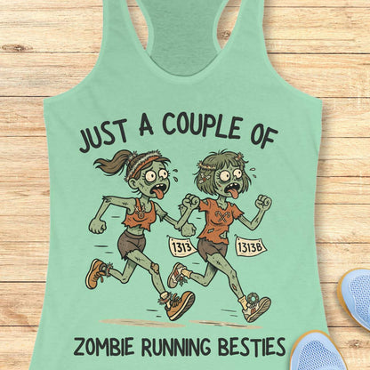 Mint green racerback tank top featuring the phrase “JUST A COUPLE OF” above two cartoon zombie runners and “ZOMBIE RUNNING BESTIES” below. The two zombie friends are running side by side wearing race bibs numbered 1313 and 1313B, with tattered running clothes, messy hair, and humorous zombie details. The playful Halloween-themed design combines friendship and running with a spooky, fun aesthetic perfect for runners who love Halloween.