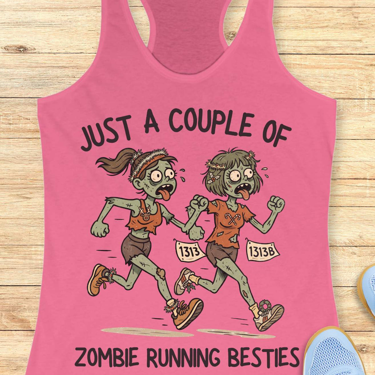 pink racerback tank top featuring the phrase “JUST A COUPLE OF” above two cartoon zombie runners and “ZOMBIE RUNNING BESTIES” below. The two zombie friends are running side by side wearing race bibs numbered 1313 and 1313B, with tattered running clothes, messy hair, and humorous zombie details. The playful Halloween-themed design combines friendship and running with a spooky, fun aesthetic perfect for runners who love Halloween.