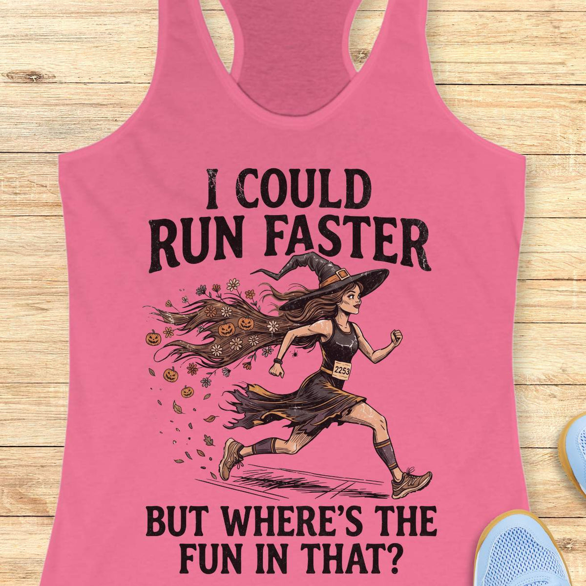 Pink racerback tank top featuring the humorous Halloween running quote, “I COULD RUN FASTER BUT WHERE’S THE FUN IN THAT?” The design shows a witch runner wearing a pointed hat, flowing tattered dress, and race bib number 2253, sprinting forward. Her long hair trails behind her, filled with autumn leaves, flowers, and small jack-o'-lanterns, creating a magical motion effect. The artwork combines running motivation with spooky Halloween charm, making it perfect for runners who prefer enjoying the journey over