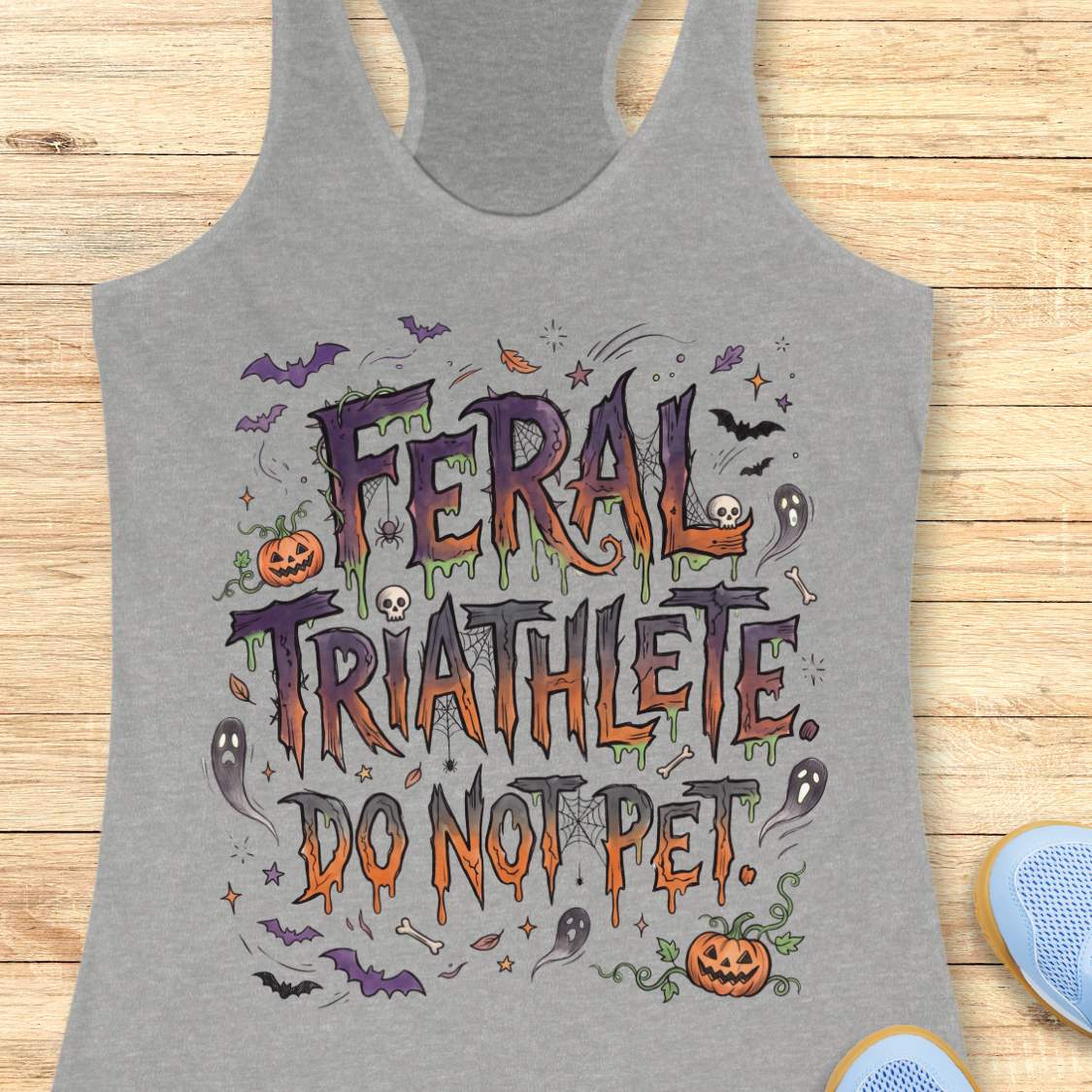 Funny Halloween running grey tank top featuring the slogan “Feral Triathlete Do Not Pet” in spooky dripping typography surrounded by bats, ghosts, pumpkins, spider webs, and Halloween elements. Humorous athletic apparel for women runners, triathletes, marathoners, and Halloween race participants.
