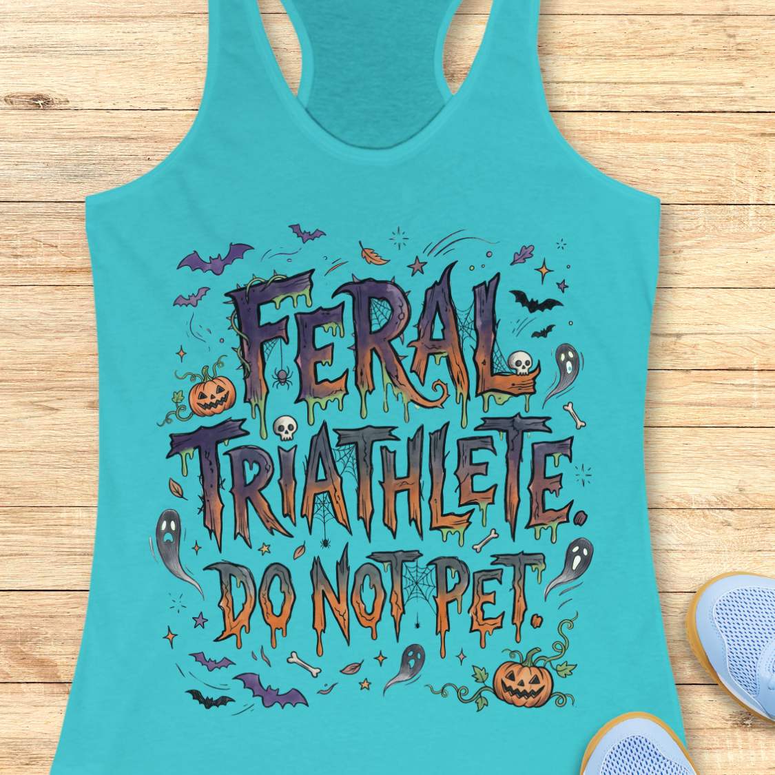 Funny Halloween running blue tank top featuring the slogan “Feral Triathlete Do Not Pet” in spooky dripping typography surrounded by bats, ghosts, pumpkins, spider webs, and Halloween elements. Humorous athletic apparel for women runners, triathletes, marathoners, and Halloween race participants.
