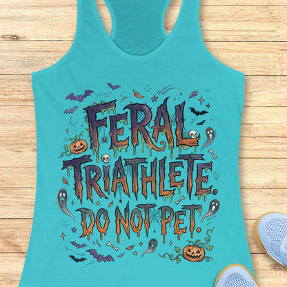 Funny Halloween running blue tank top featuring the slogan “Feral Triathlete Do Not Pet” in spooky dripping typography surrounded by bats, ghosts, pumpkins, spider webs, and Halloween elements. Humorous athletic apparel for women runners, triathletes, marathoners, and Halloween race participants.