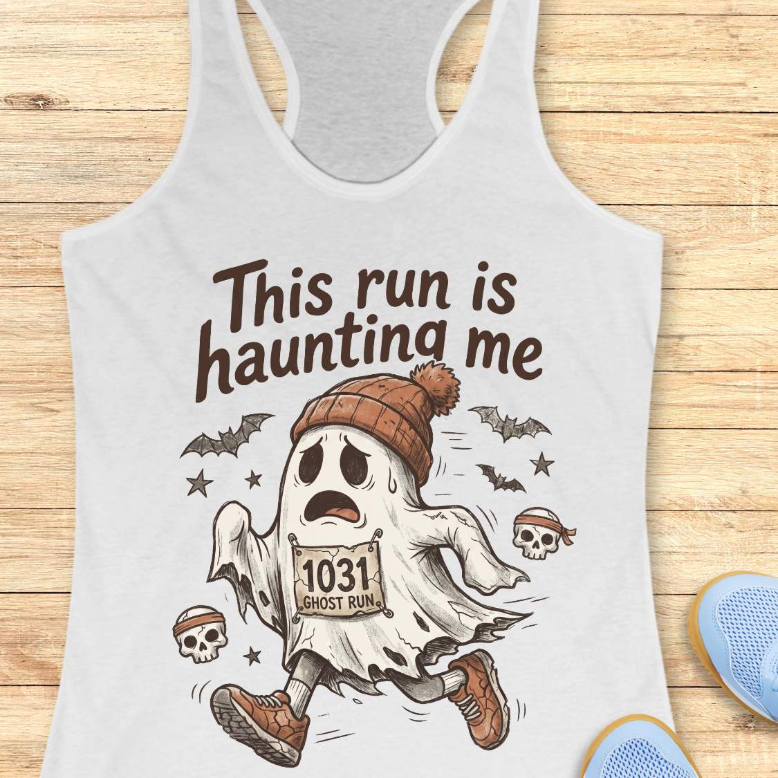 white Halloween tank top with an image of a running ghost and text 'This run is haunting me', on a wooden surface