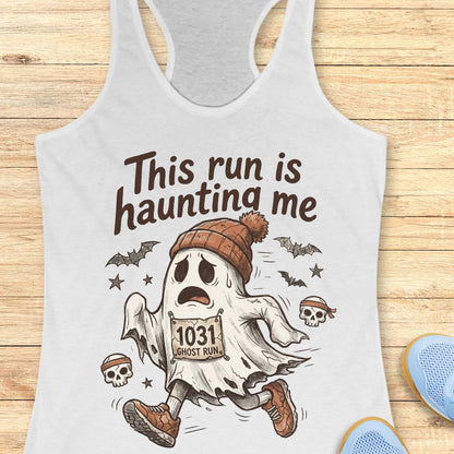 white Halloween tank top with an image of a running ghost and text 'This run is haunting me', on a wooden surface