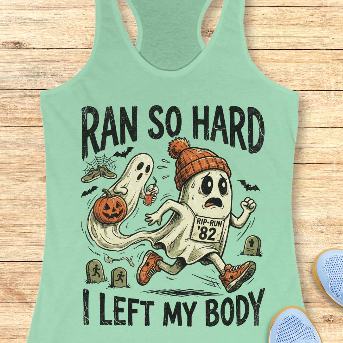 mint Halloween tank top with an image of a running ghost and text 'Ran so hard I left my body', on a wooden surface