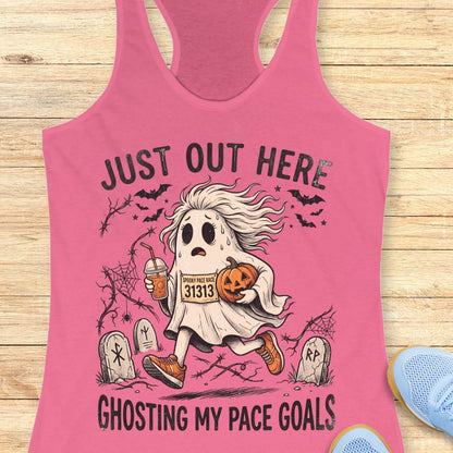 pink Halloween tank top with an image of a running ghost and text 'Just out here ghosting my pace goals', on a wooden surface